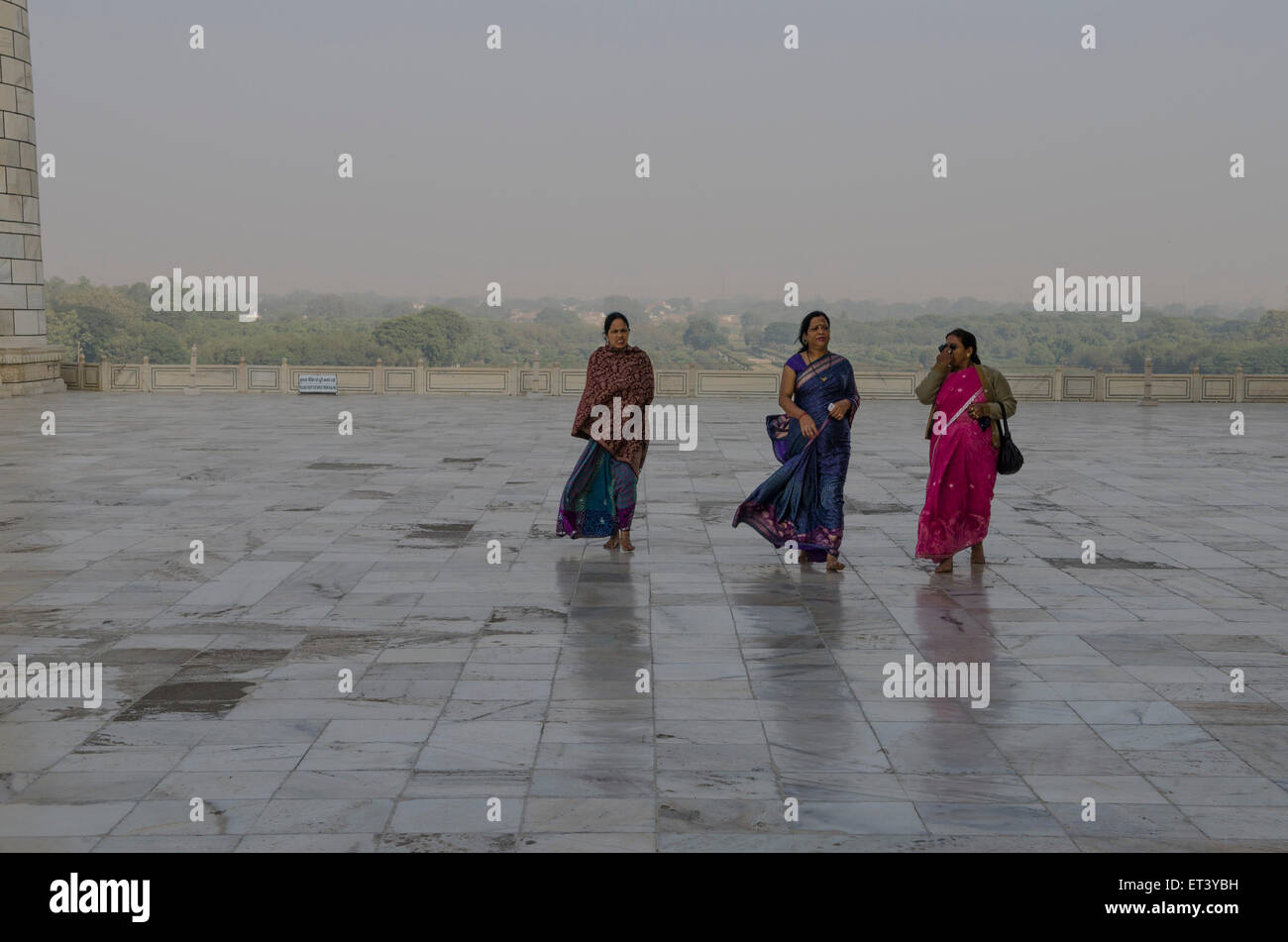 Tre vestito tradizionale delle donne a piedi lungo il pavimento in marmo lucido del Taj Mahal Foto Stock