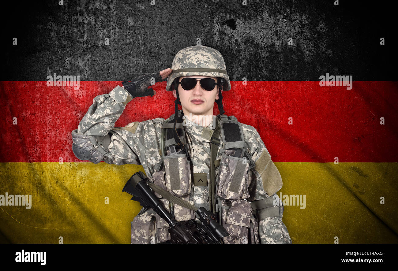 Soldato saluta la bandiera della Germania sullo sfondo Foto Stock