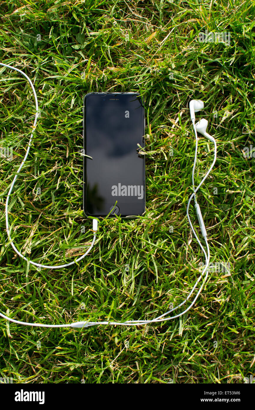 Telefono cellulare con auricolare sull'erba. Foto Stock