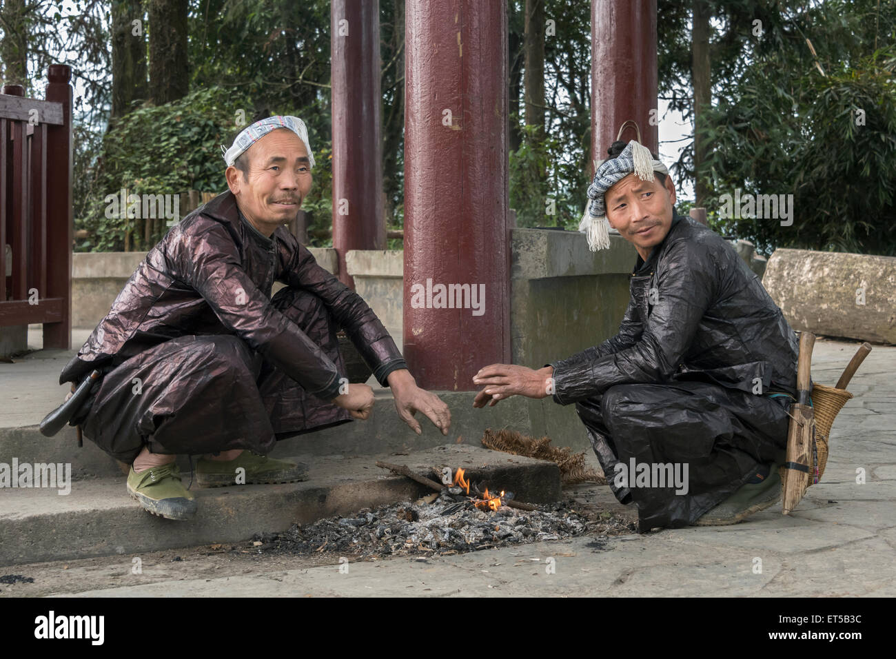 Ethinic Miao uomini riscalda le loro mani su un piccolo incendio, Basha Gun Village, Guizhou, Cina Foto Stock