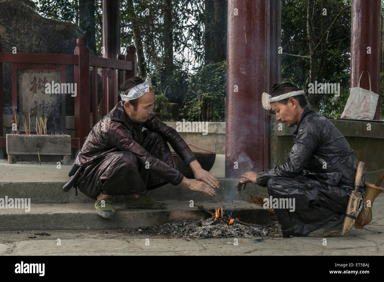Basha Miao etnica uomini riscalda le loro mani su un fuoco, Basha Gun Village, Guizhou, Cina Foto Stock