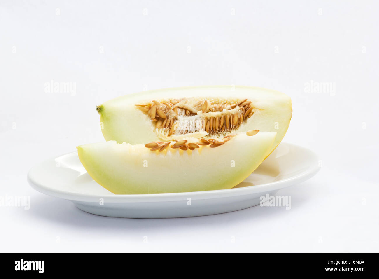 Canarie a fette di melone in una piastra su sfondo bianco Foto Stock