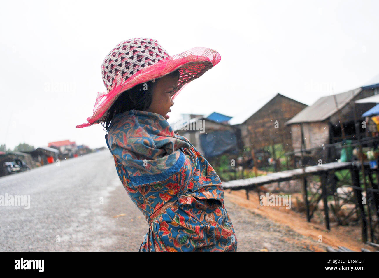 Una ragazza cambogiana sotto la pioggia al villaggio galleggiante sul lago Tonle Sap vicino a Siem Reap, Cambogia. Foto Stock