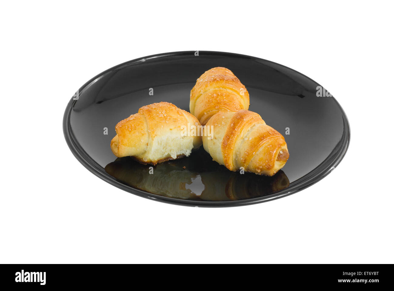 Tre piccoli croissant su una piastra nera. Foto Stock