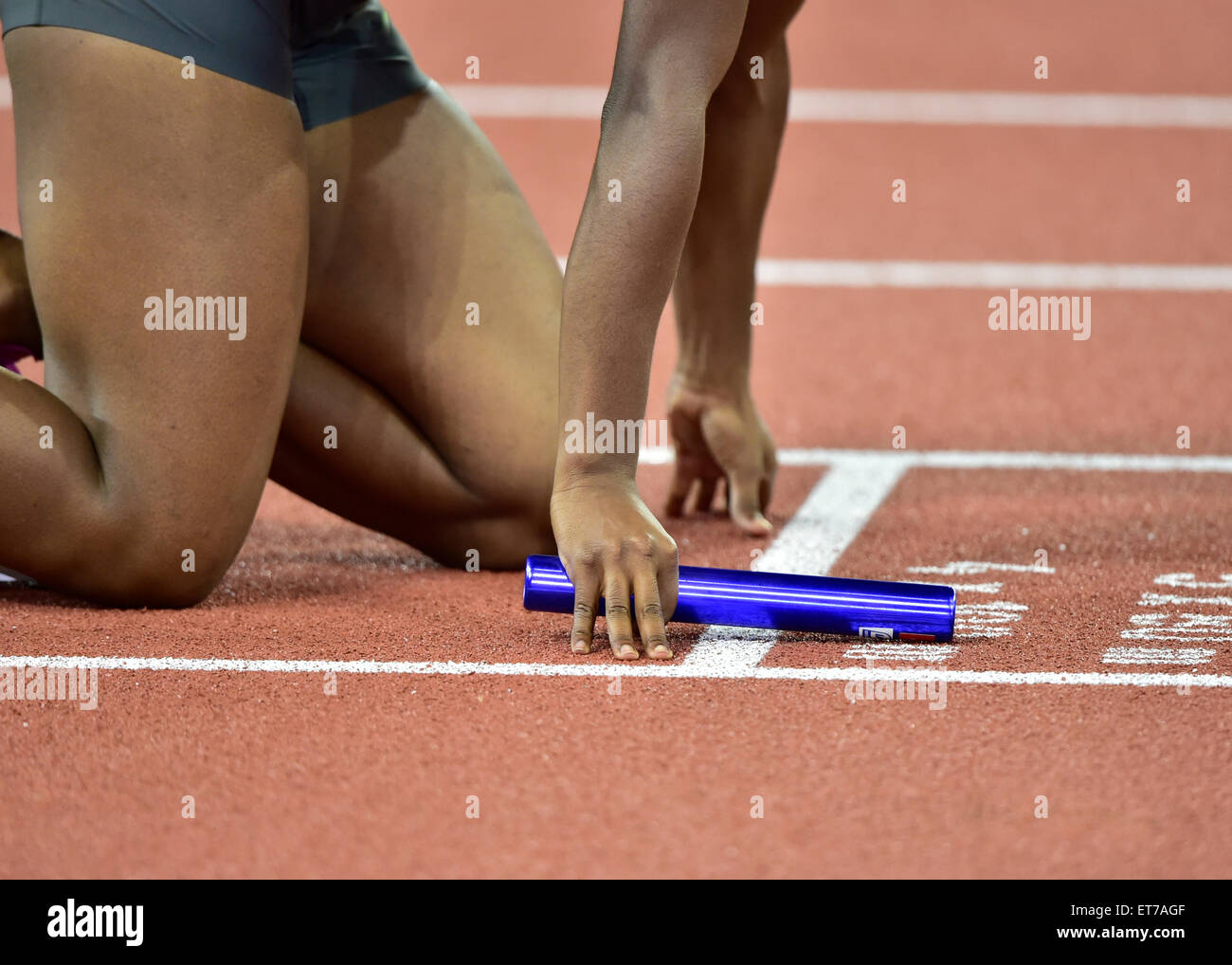 Un atleta femminile (etnia africana) tenendo un testimone è sempre impostato su pista appena prima dell'inizio di una staffetta Foto Stock
