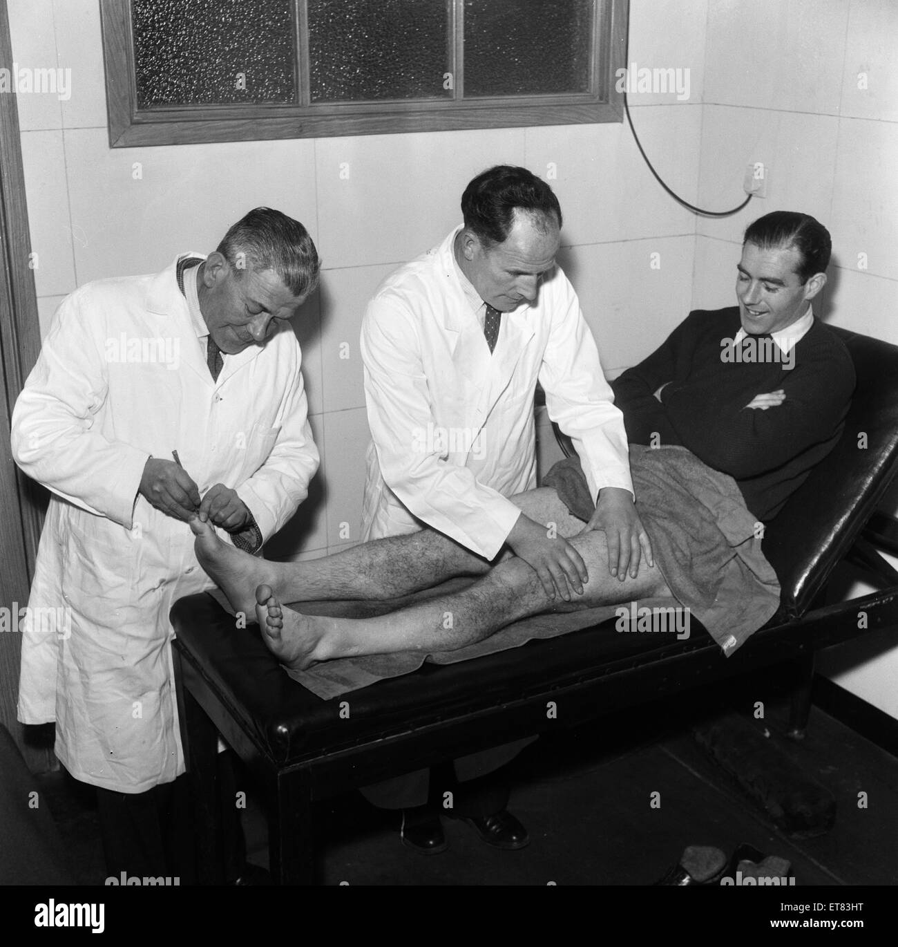 Wilf Dixon (centro), Southend Regno Trainer massaggi player Sam McCrory sulla tabella di trattamento, con Henry un cuoco (sinistra) un ben noto pedicure, 16 gennaio 1957. Foto Stock