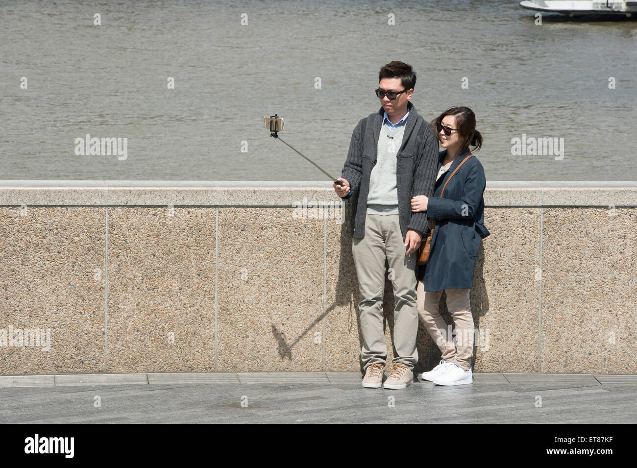 I turisti giapponesi a scattare foto in Londra con fotocamere, telefoni e bastoni selfie Foto Stock