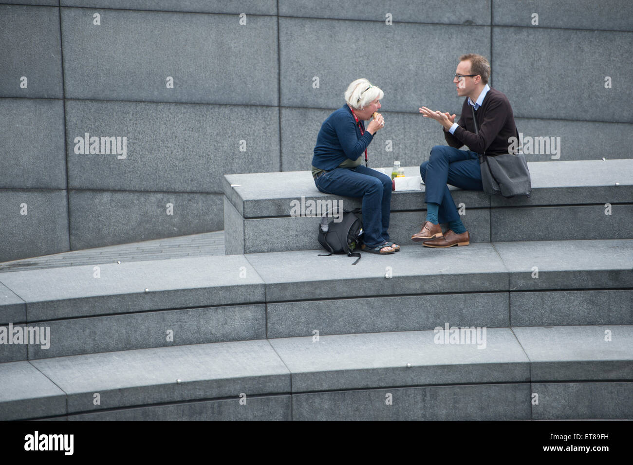 2 persone mangiare il pranzo sui gradini in corrispondenza di più di Londra accanto alla City Hall durante la pausa pranzo al lavoro Foto Stock
