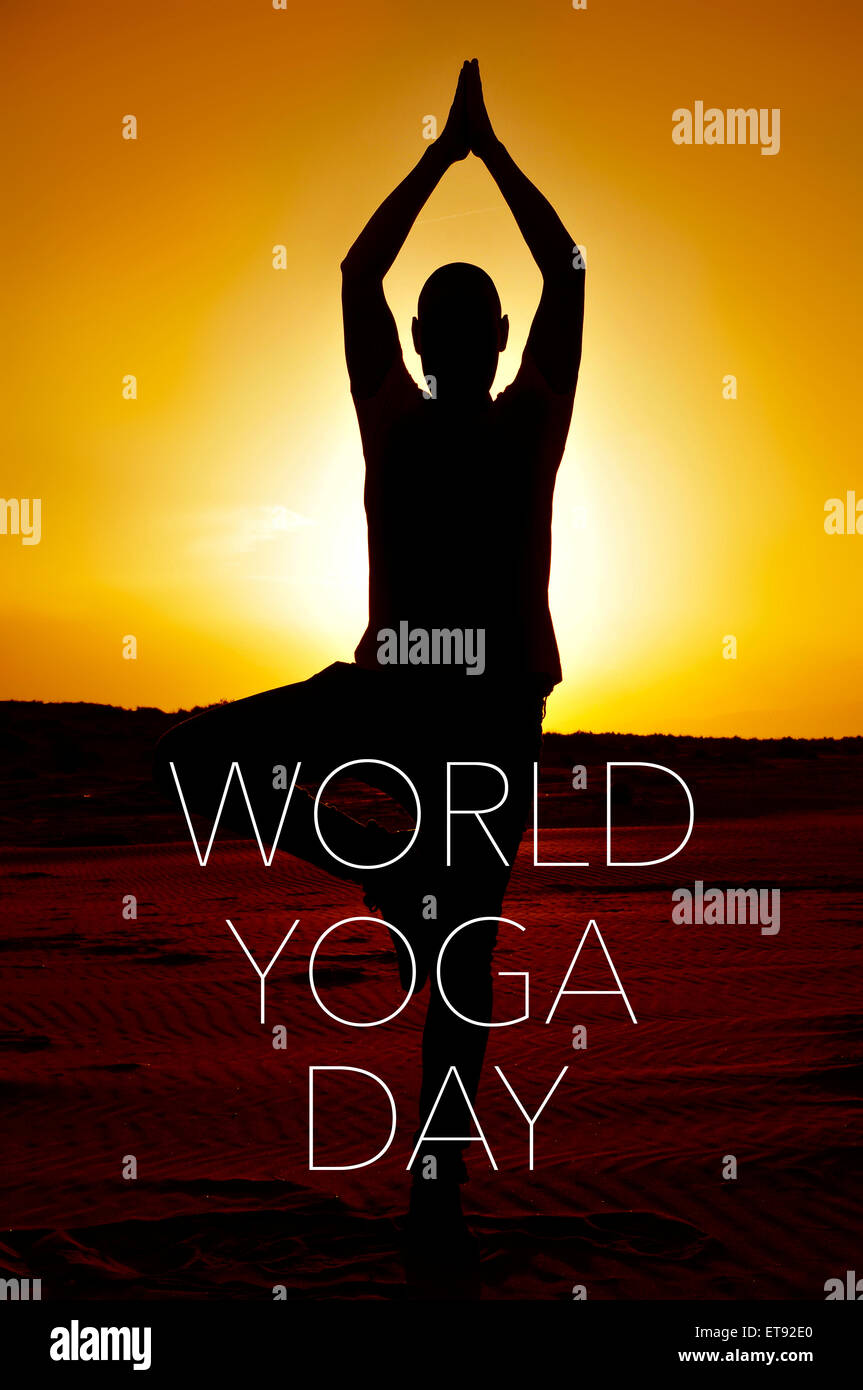Un giovane uomo yogi praticando la posizione dell'albero all'aperto in controluce al tramonto e il testo world yoga giorno Foto Stock