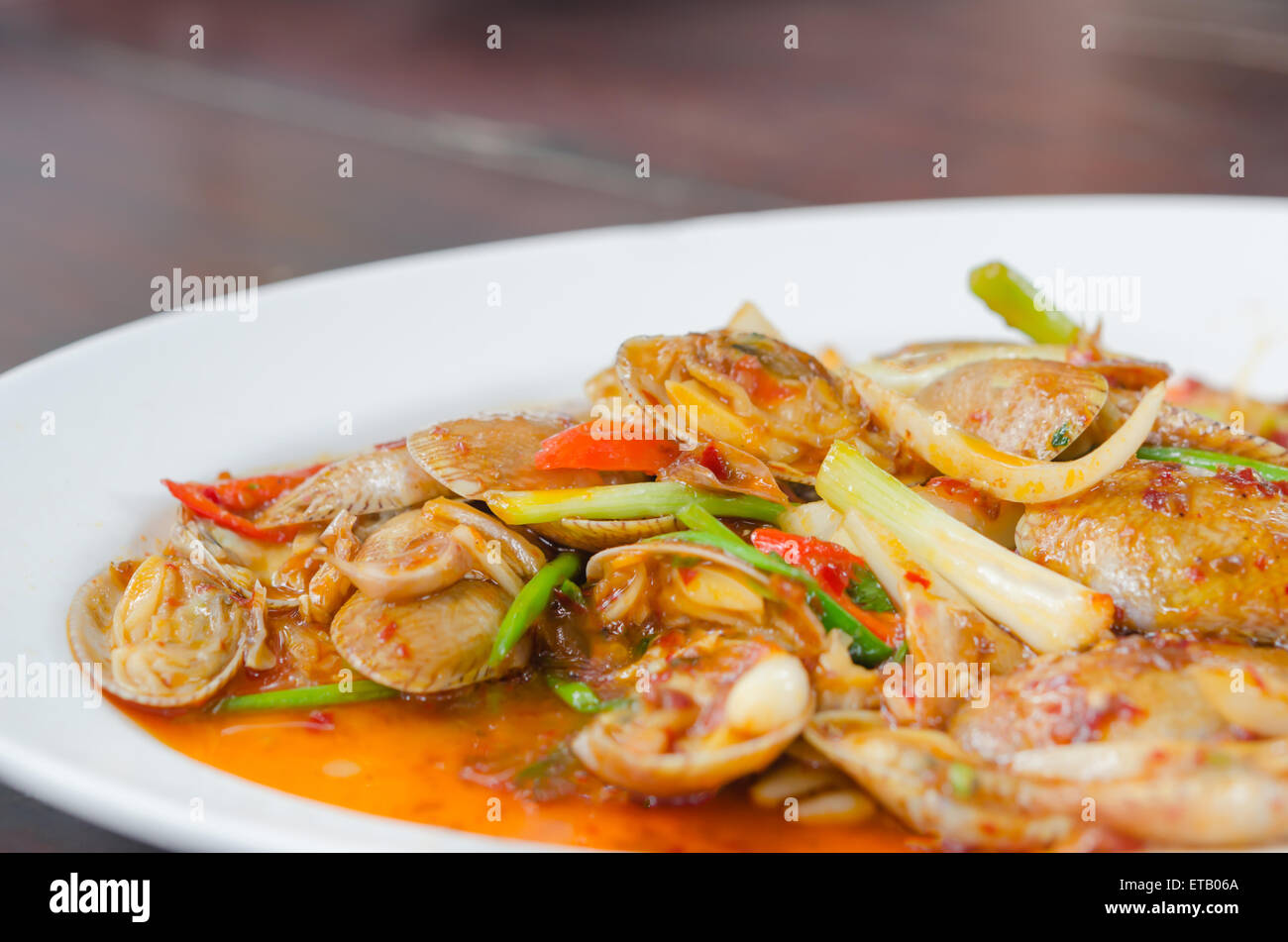 Saltate in padella le vongole con arrosti di pasta di peperoncino tailandese e le foglie di basilico Foto Stock
