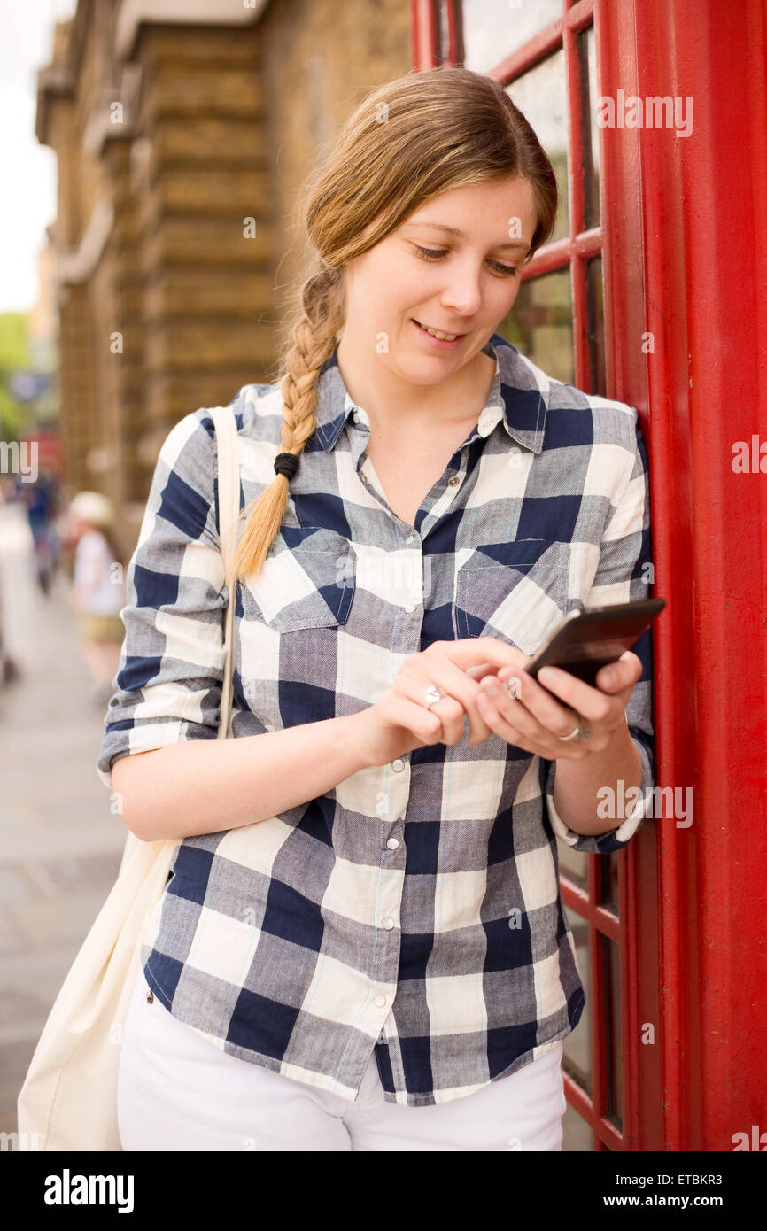 Giovane donna inviando un messaggio di testo a Londra Foto Stock