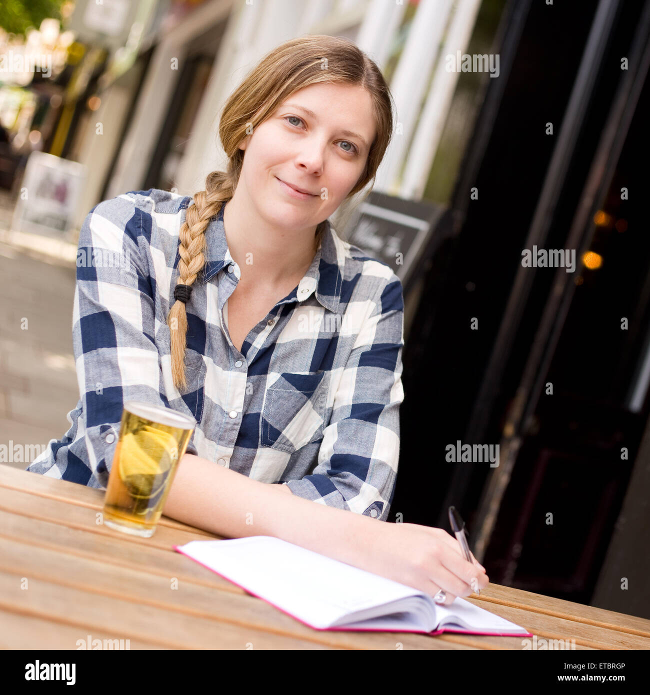 Giovane donna gustando un drink con il suo diario Foto Stock