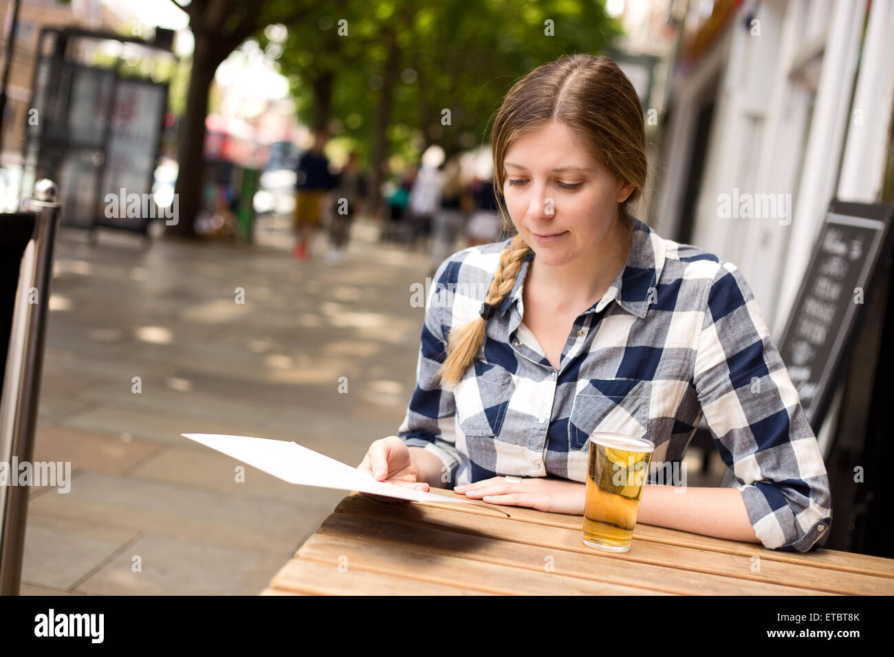 Giovane donna lettura del menu in una barra Foto Stock