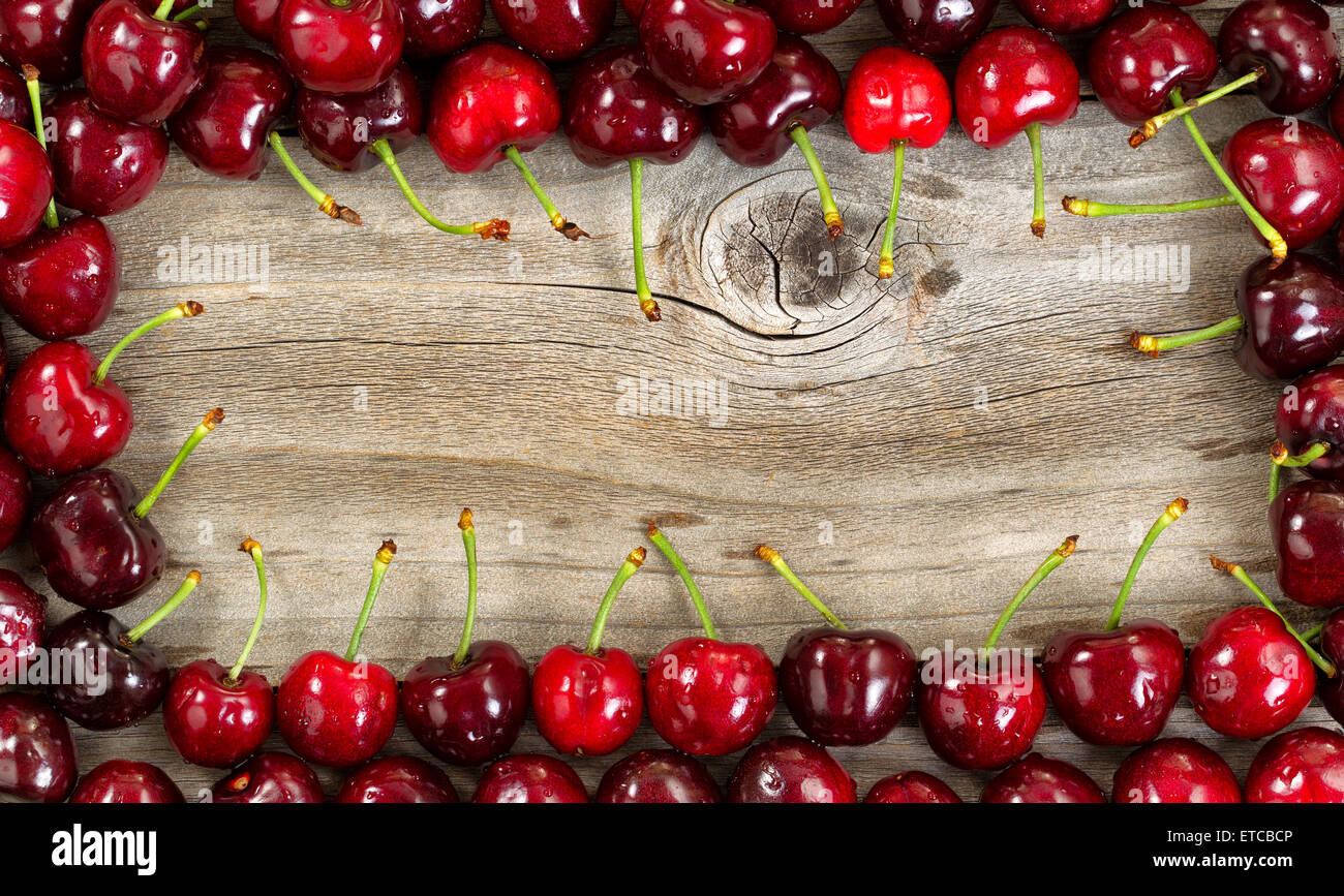 Confine di ripe grandi ciliegie nero su legno rustico. Foto Stock