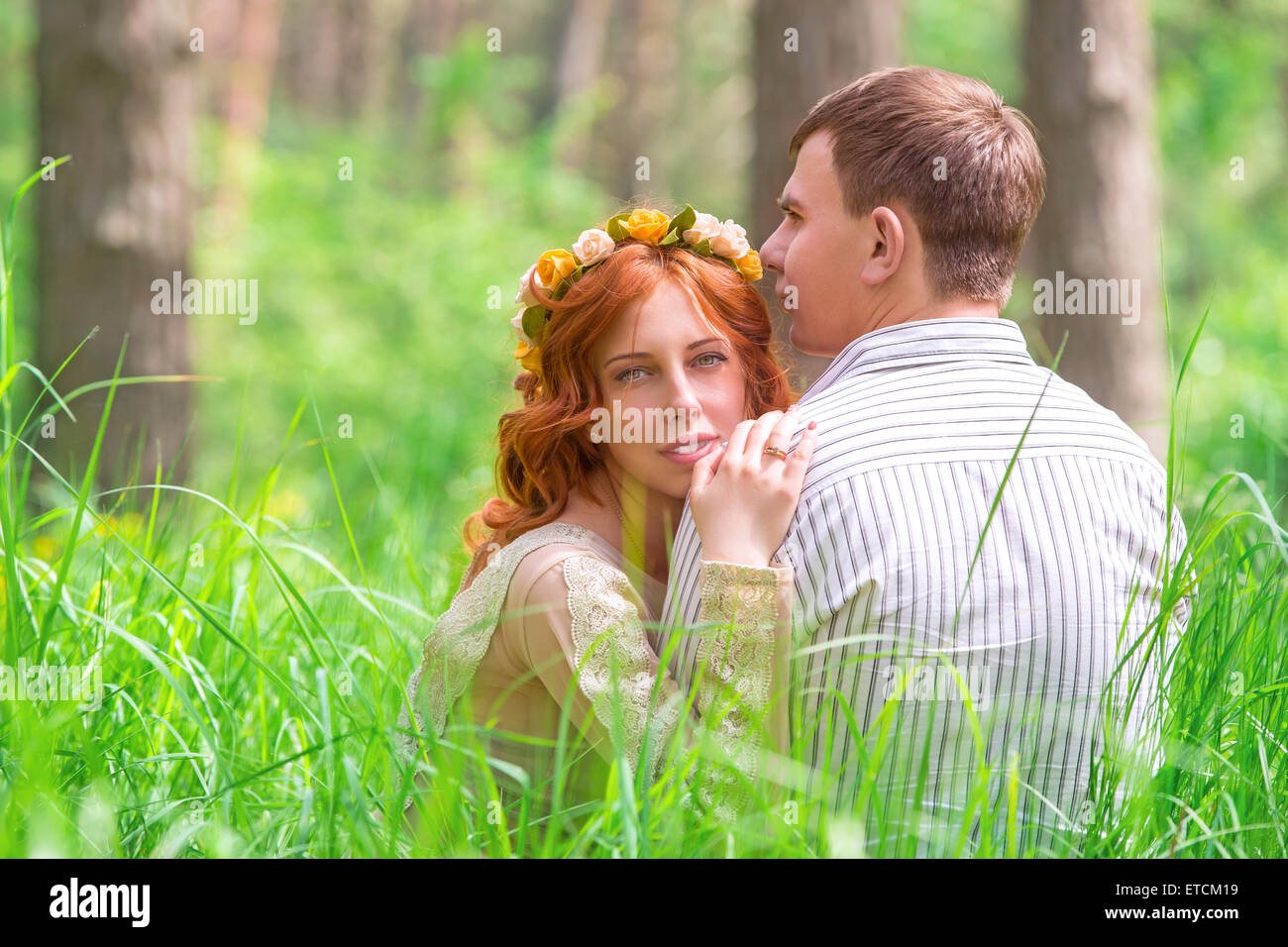 Gli amanti della bella seduta su erba in foresta, appoggiata all'aperto, dolce romantica sentimenti, felice giorno di nozze, giovani nuova famiglia Foto Stock