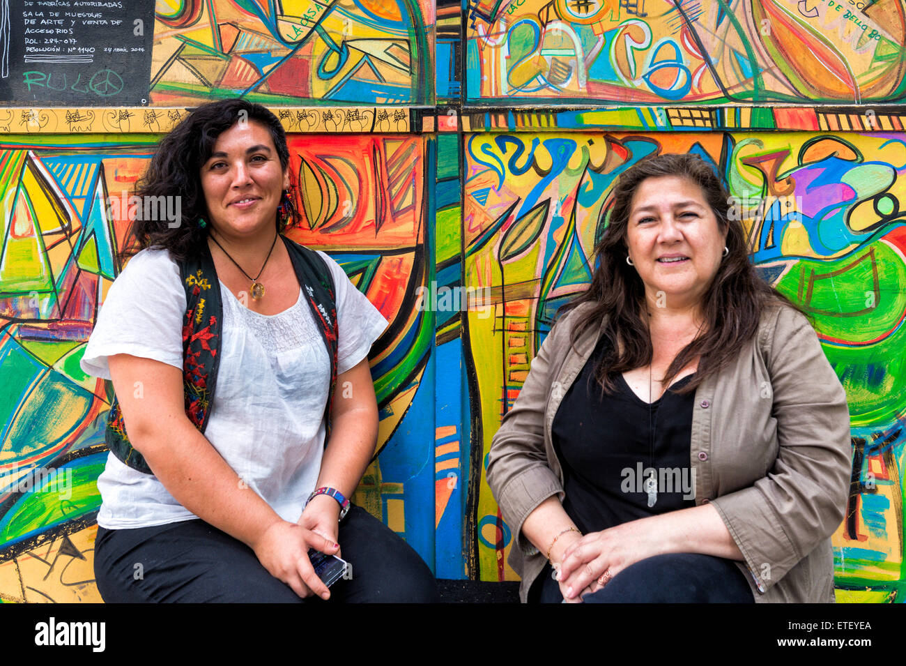 Due donne di fronte ad una parete ricoperta di graffiti, Quartiere Bellavista, Santiago del Cile Foto Stock