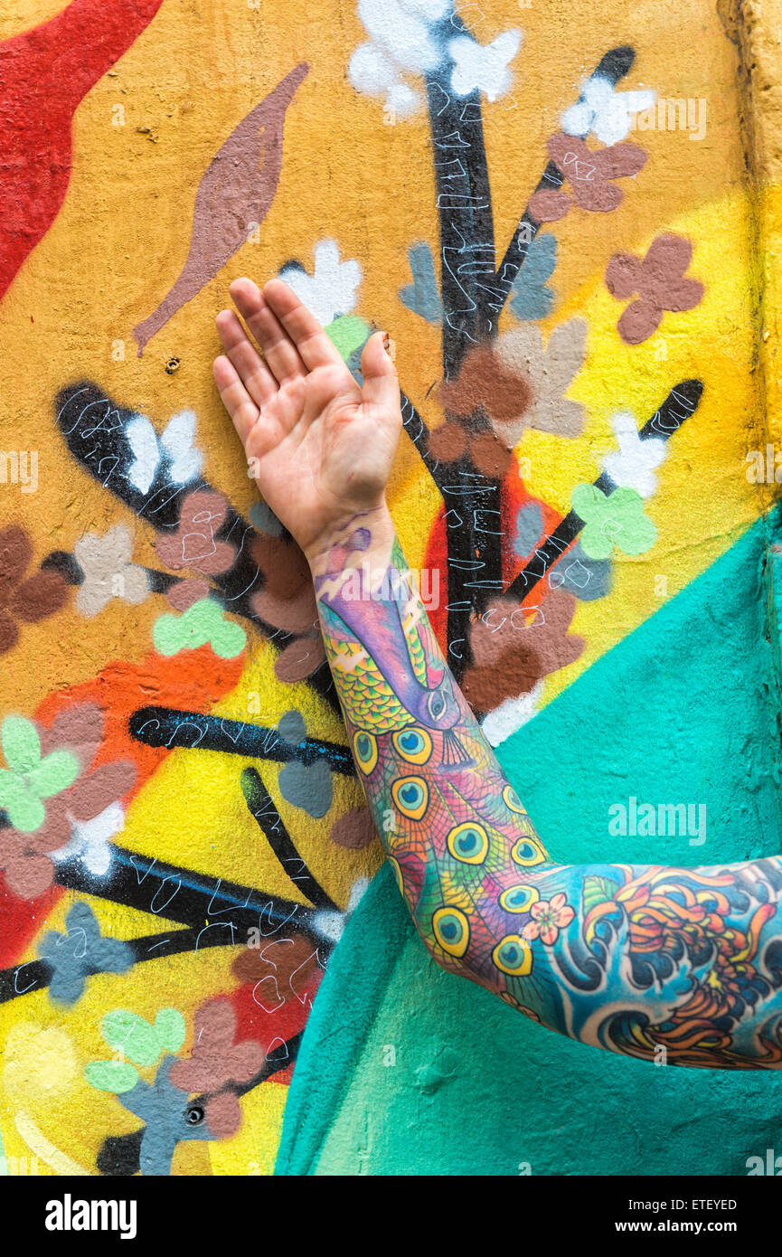Tatuato donna di fronte a un muro coperto di graffiti, Quartiere Bellavista, Santiago del Cile Foto Stock