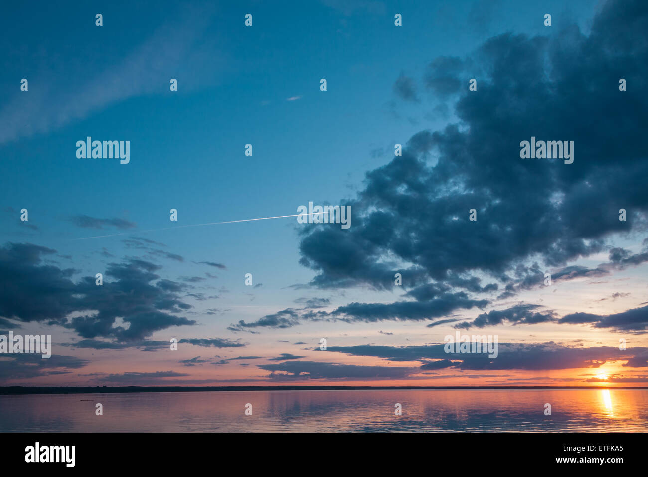 Il piano a getto è dietro il tramonto nuvole sopra il lago di sera Foto Stock