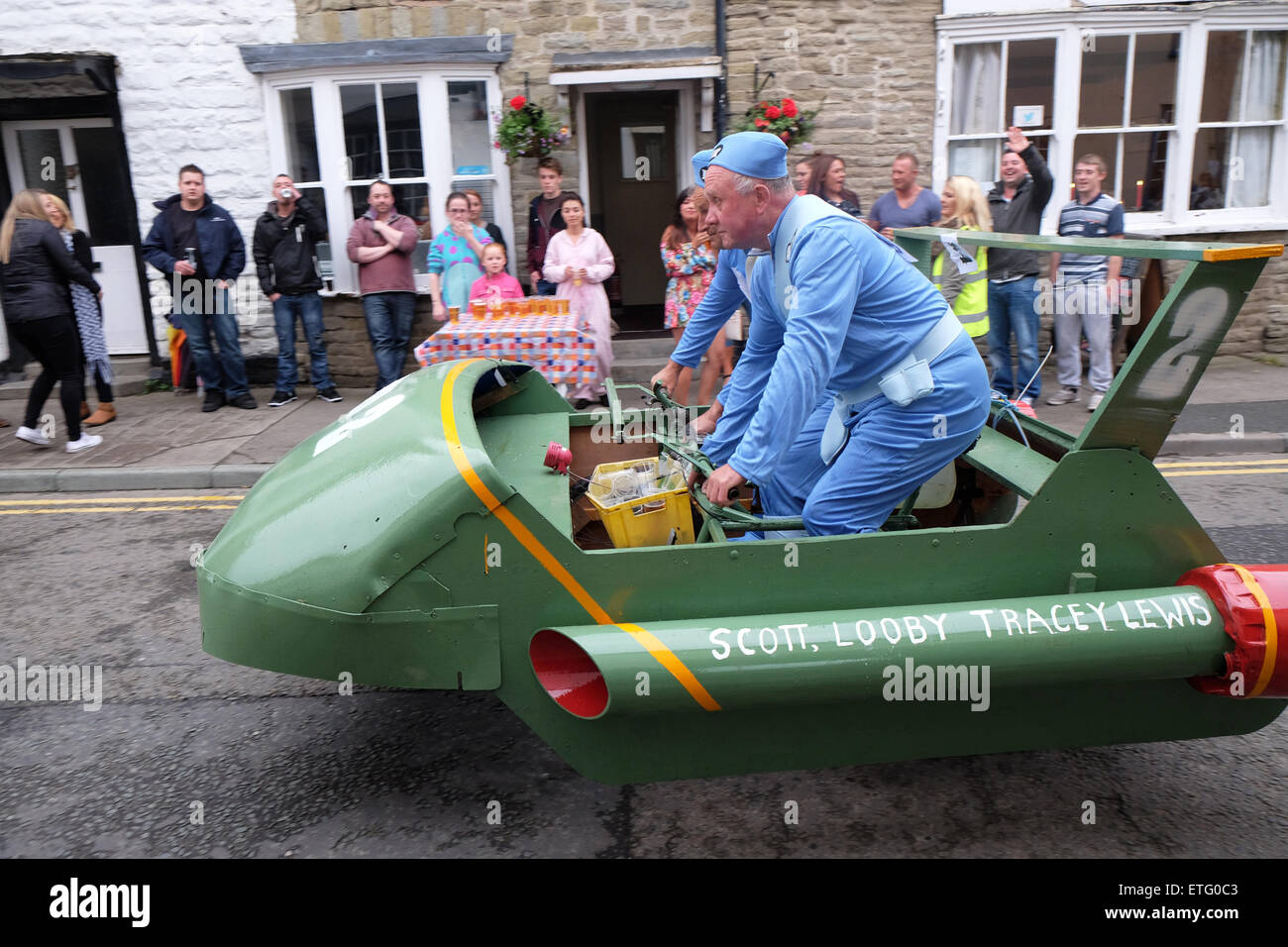 Kington, Herefordshire, UK. Xiii Giugno, 2015. Kington Festival carriola gara concorrenti in questo anni 39th carriola gara disputatasi intorno alla città di fermarsi per bere in ogni pub en route. Qui i concorrenti vestiti come Thunderbirds interrompere per un rapido mezzo di birra in città. Carriole e pedale powered macchine sono autorizzati a inserire l'evento. Foto Stock