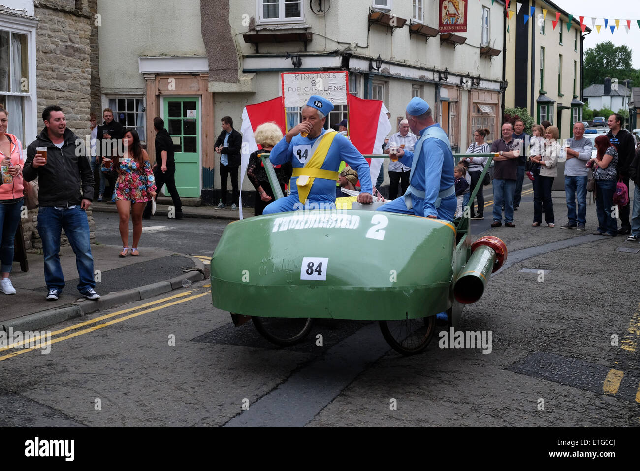 Kington, Herefordshire, UK. Xiii Giugno, 2015. Kington Festival carriola gara concorrenti in questo anni 39th carriola gara disputatasi intorno alla città di fermarsi per bere in ogni pub en route. Qui i concorrenti vestiti come Thunderbird 2 caratteri di arresto per un rapido mezzo di birra in città. Carriole e pedale powered macchine sono autorizzati a inserire l'evento. Foto Stock