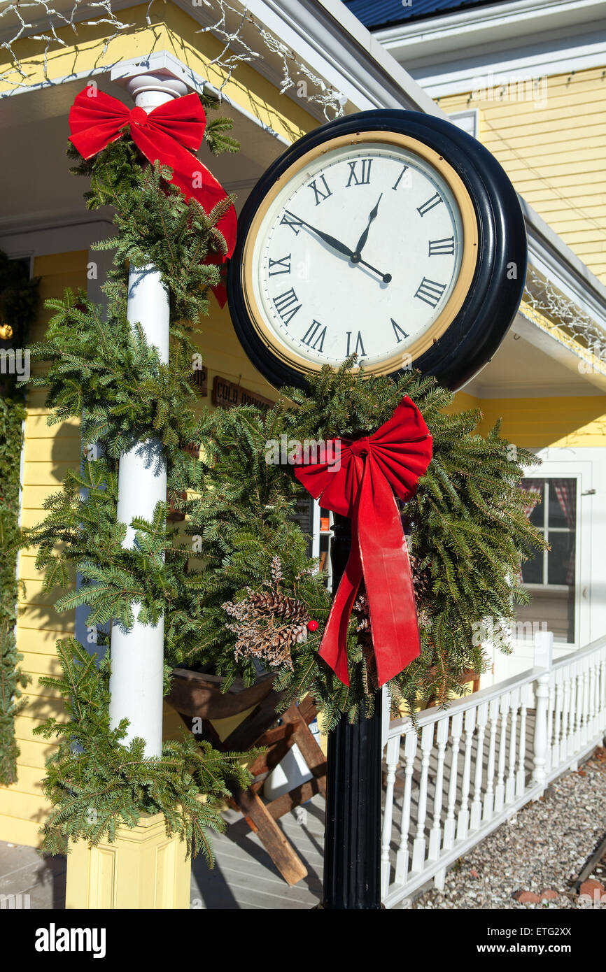 Un alto piedistallo nero orologio è decorato per il Natale con la ghirlanda di sempreverdi e fiocco rosso. Foto Stock