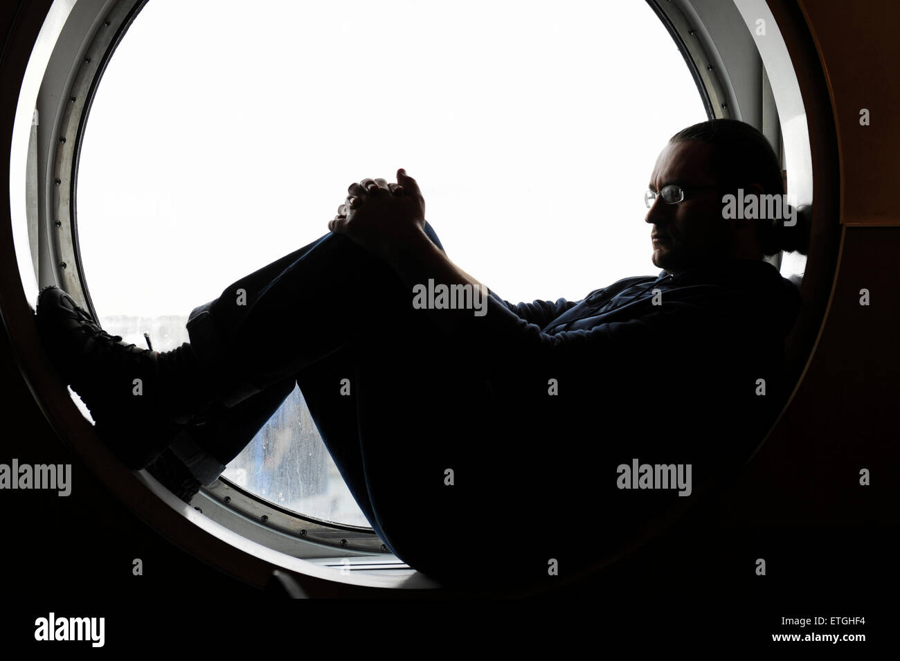 Uomo seduto in un oblò di una nave in Inghilterra in Europa Foto Stock