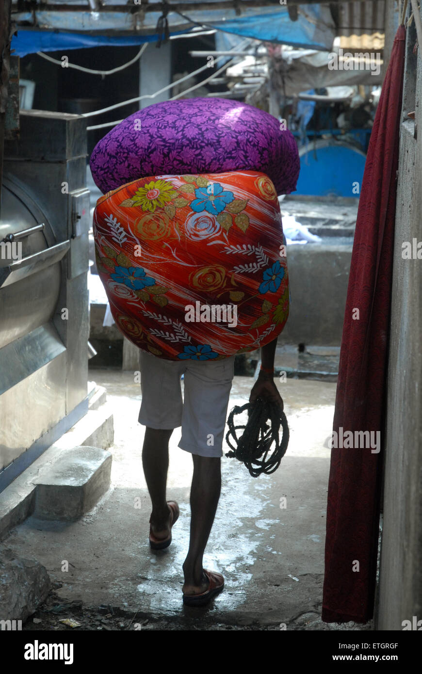 L'uomo la sacca di custodia di lavaggio di vestiti a Mahalaxmi Dhobi Ghat aperto lavanderia a gettoni, Mumbai, Maharashtra, India. Foto Stock