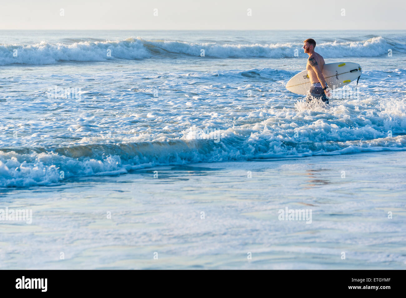 Florida surfer entra nell'oceano poco dopo l'alba a prendere un po' di mattina presto le onde a Jacksonville Beach. Foto Stock