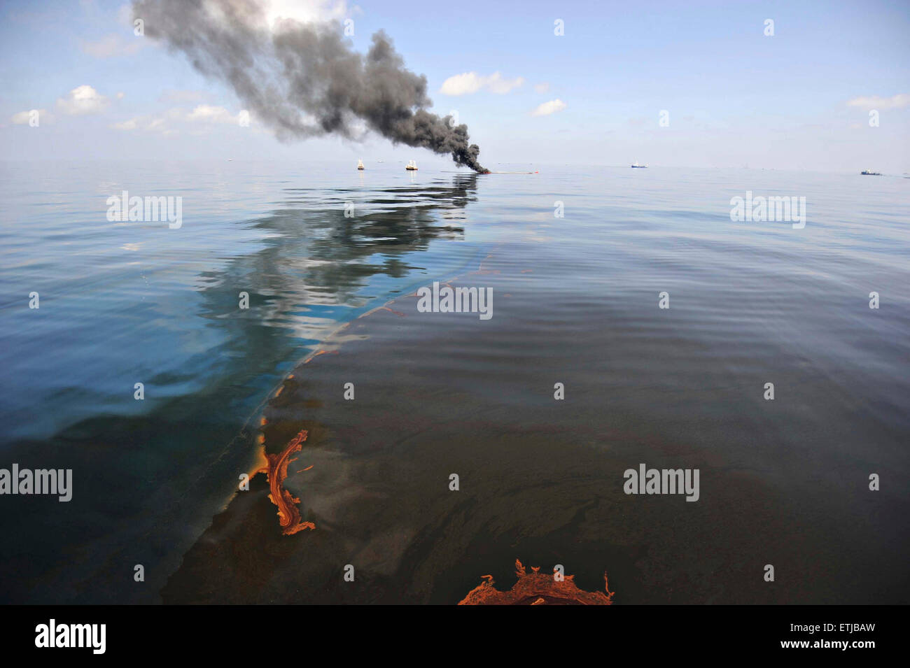 Nuvole scure riempiono il cielo come clean up equipaggi di condotta ustioni controllata di olio raccolte dalla superficie del Golfo del Messico a seguito della BP Deepwater Horizon oil spill disastro come gli sforzi per contenere e pulire i milioni di galloni di equipaggio continuare il 6 maggio 2010 nel Golfo del Messico. Foto Stock