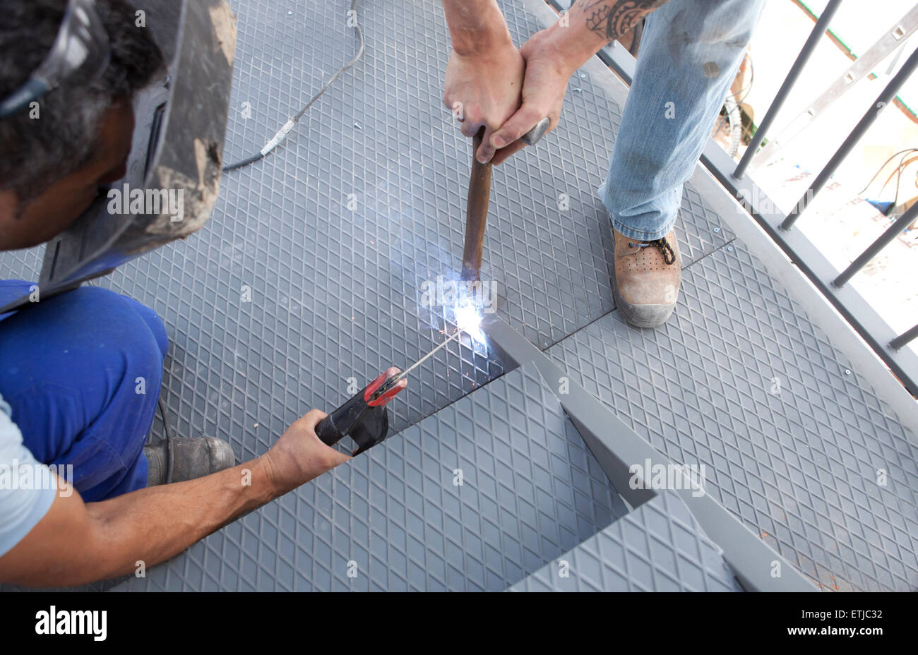 Due uomini al lavoro sulla piattaforma di ferro con saldatura ad arco Foto Stock