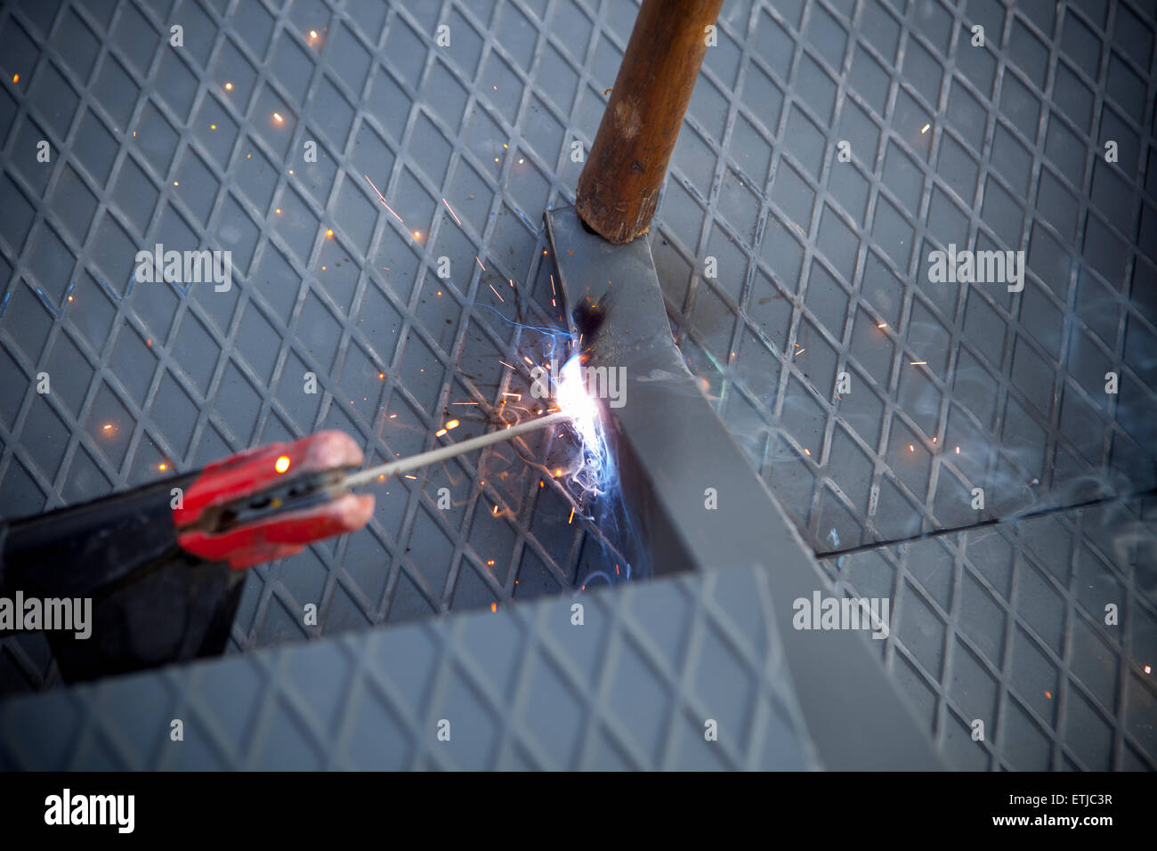 Due uomini al lavoro sulla piattaforma di ferro con saldatura ad arco Foto Stock
