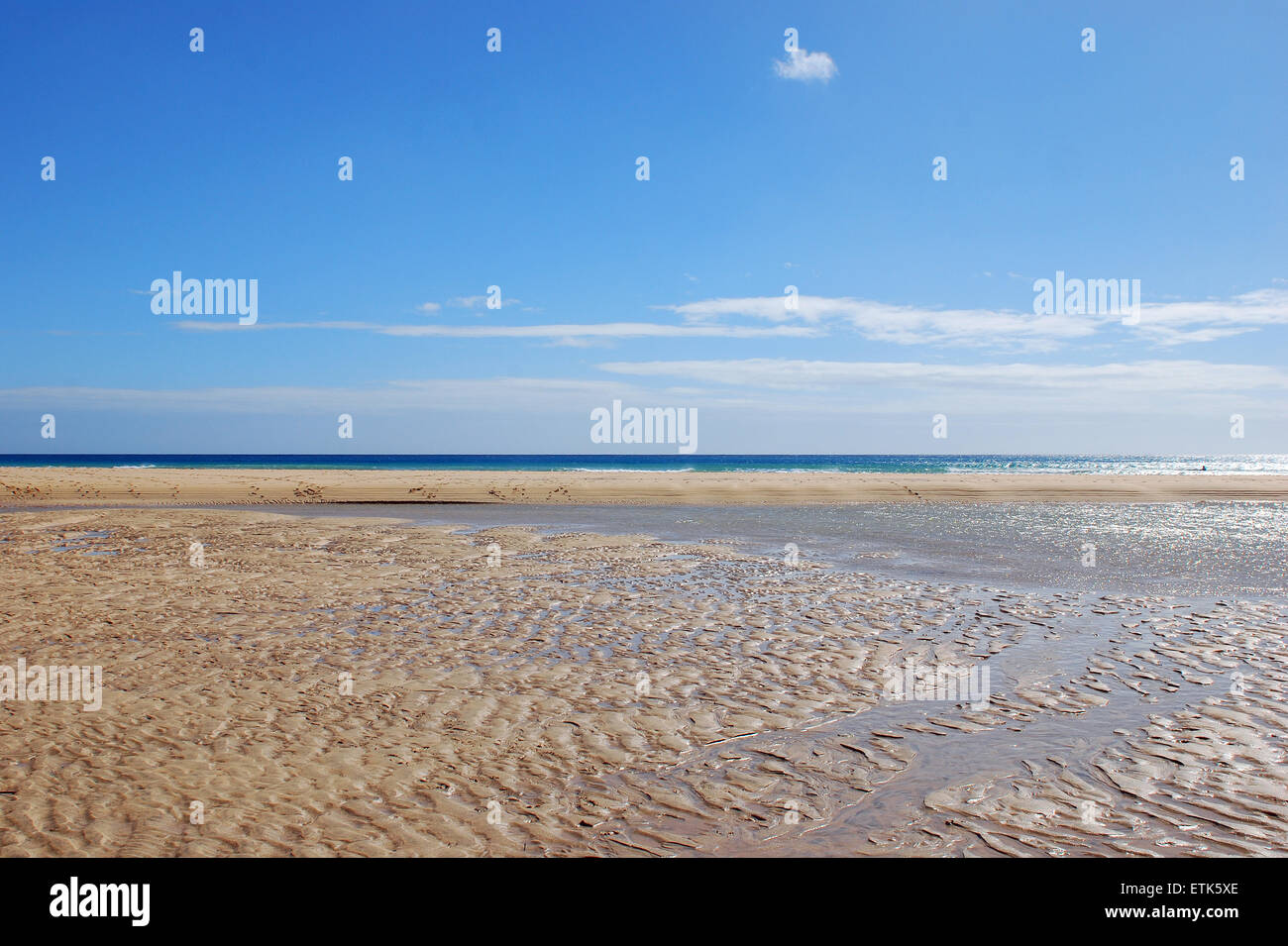 Fuerteventura Isole Canarie. Una spiaggia bagnata in una giornata di sole con il mare all'orizzonte, dove l'acqua ha formato piccole pozzanghere, Foto Stock