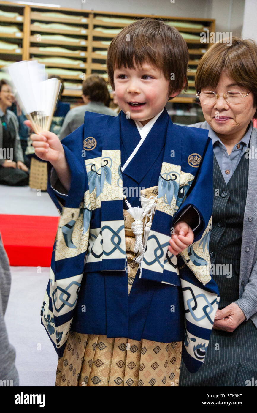 Interno con il Giapponese donna matura medicazione giovani razza mista Japanese-English bambino, ragazzo, 5 anno di età, in blu e crema kimono. Foto Stock