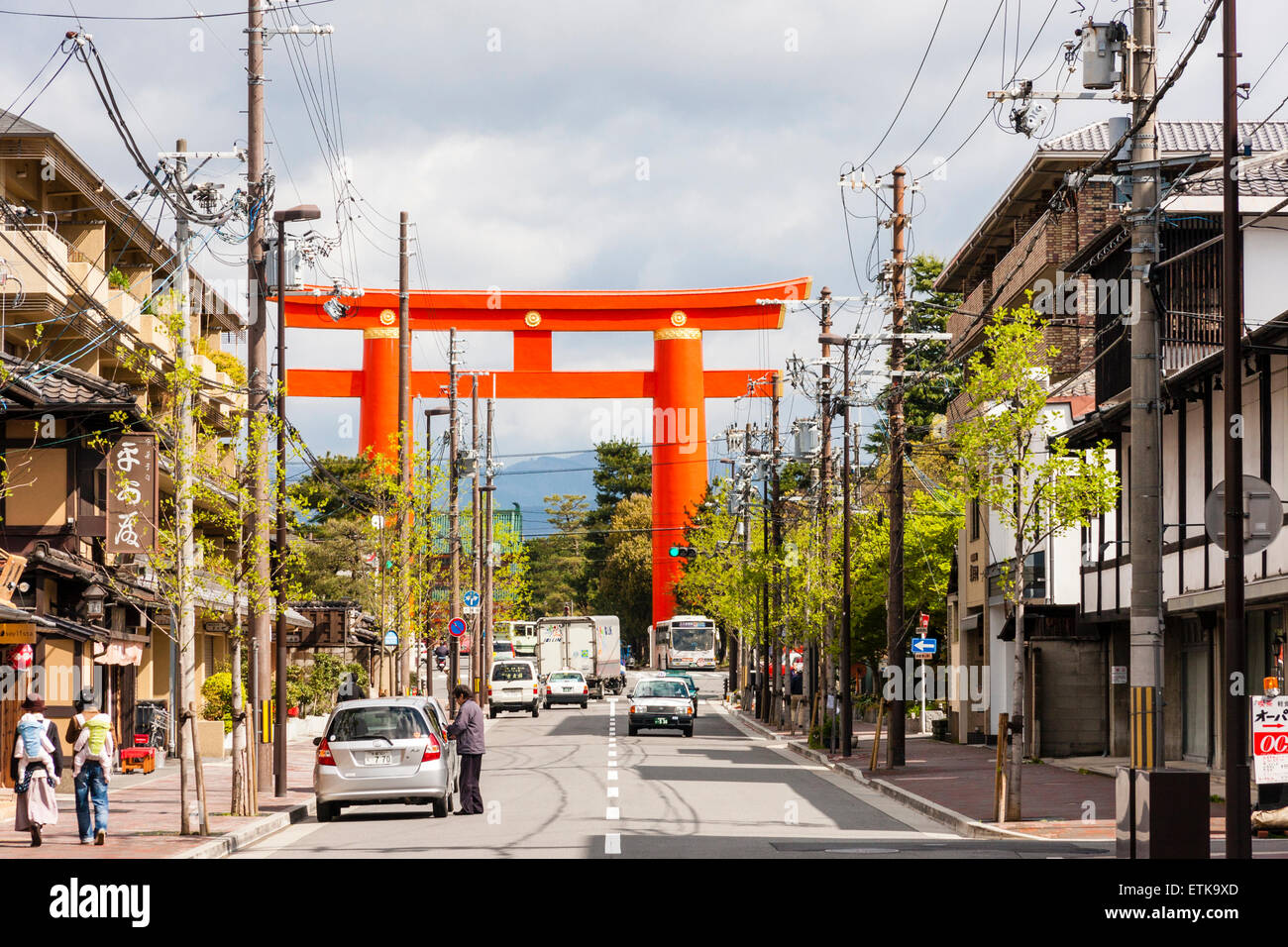 Strada principale con edifici su entrambi i lati che conducono all'imponente porta di vermiglio torii che segna l'approccio al santuario di Heian Jingu. Foto Stock