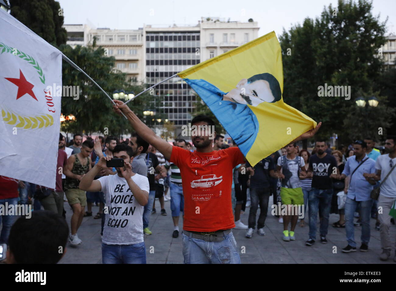 Atene, Grecia. 14 Giugno, 2015. Un uomo sventola una bandiera con la foto di Abdullah Ocalan su di essa e una bandiera della Unione democratica da parte della Siria a vittoria festeggiamenti di HDP in Atene. La gente turca che vive in Grecia ha celebrato il successo di Il Partito democratico popolare (HDP) nelle recenti elezioni generali turche dello. La sinistra e anti-nazionalista partito ha vinto 13.12% nelle ultime elezioni turche, scavalcando la soglia del 10%. © Michael Debets/Pacific Press/Alamy Live News Foto Stock