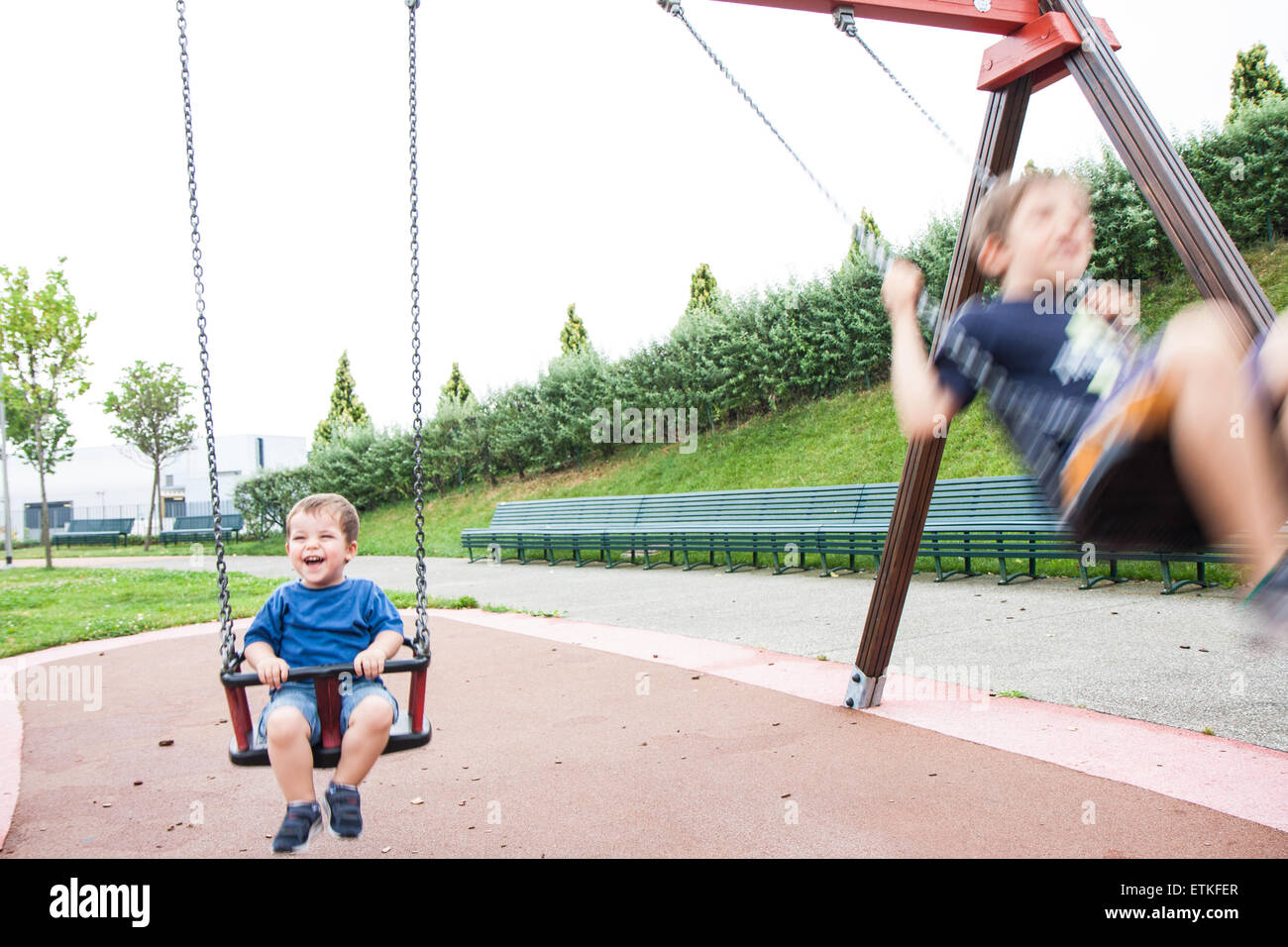 Due bambini che giocano e ridere nello swing Foto Stock