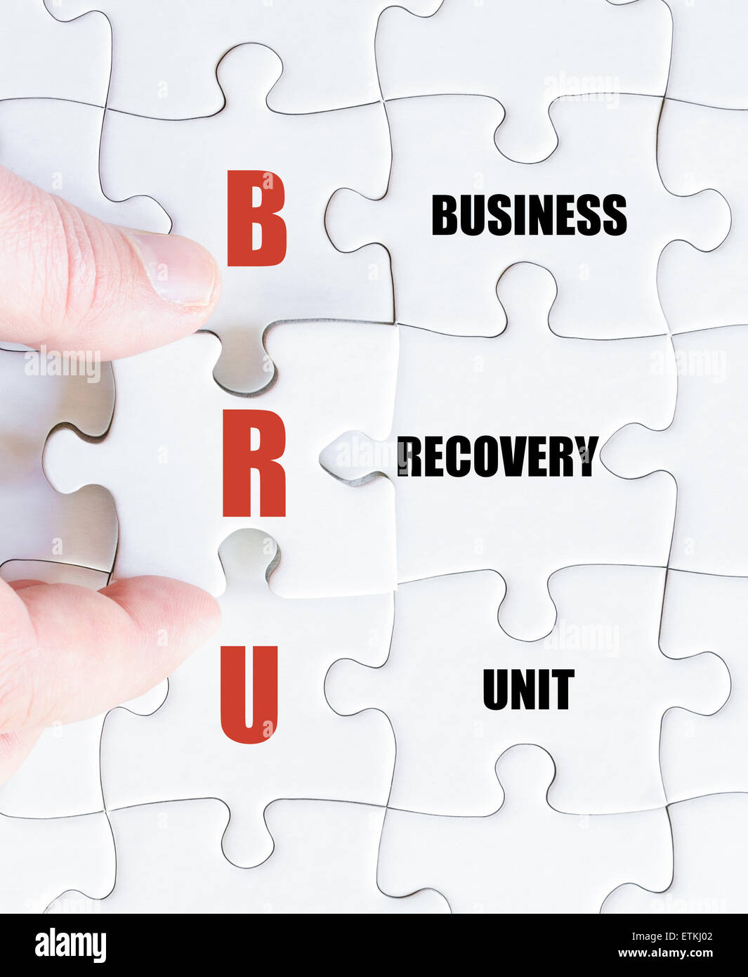 La mano di un uomo di affari di completare il puzzle con l'ultimo pezzo mancante.Concetto di immagine di Business acronimo BRU come Business Unit di recupero Foto Stock