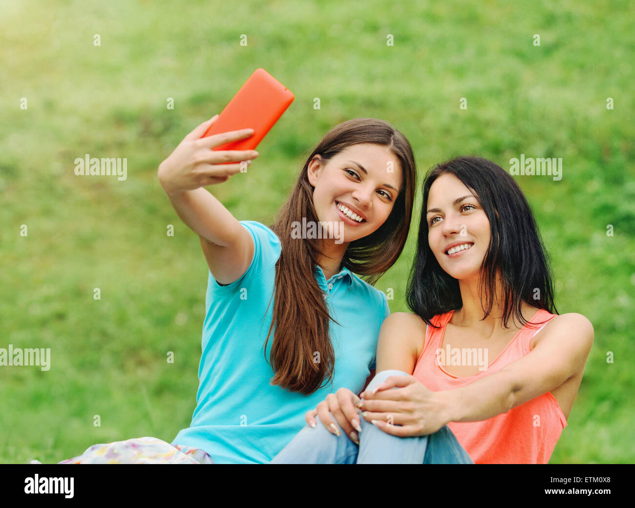 Due felici donne amici di ridere e di condivisione dei social media le immagini in uno smart phone su picnic al parco, il concetto di stile di vita Foto Stock