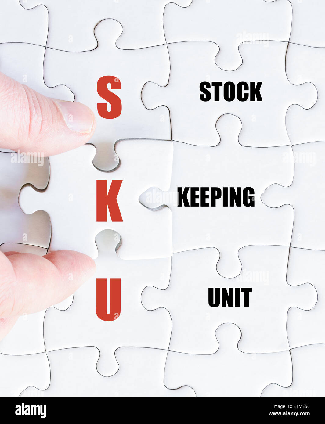 La mano di un uomo di affari di completare il puzzle con l'ultimo pezzo mancante.Concetto di immagine di Business SKU acronimo di Stock Keeping Unit Foto Stock