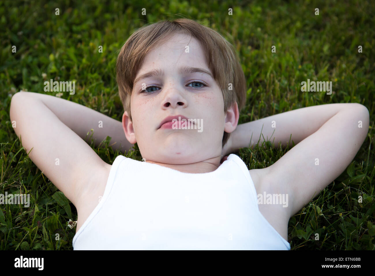 Ragazzo disteso sul prato con le mani dietro la testa Foto Stock