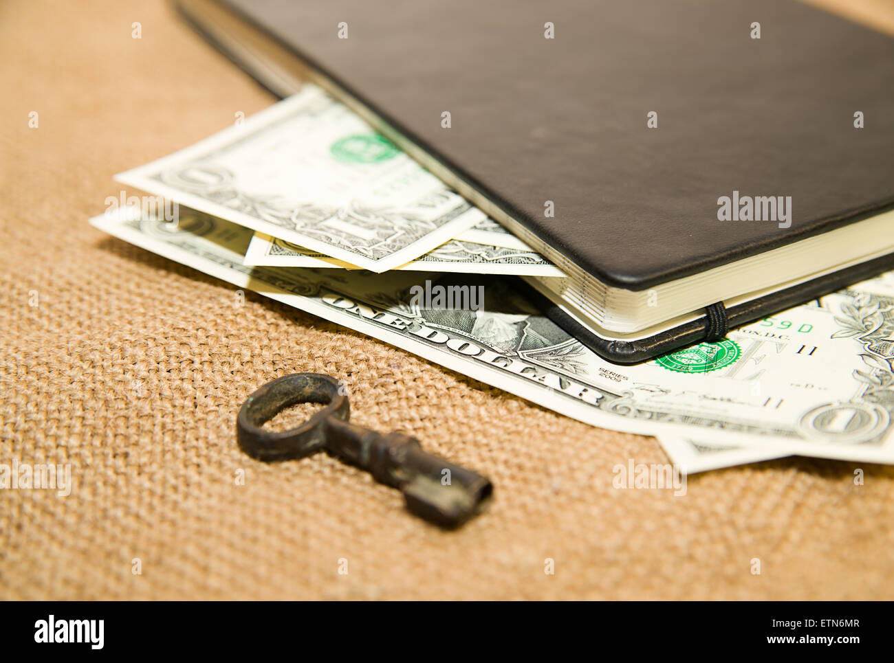 Notebook con un foglio bianco, chiave e denaro sul vecchio tessuto Foto Stock