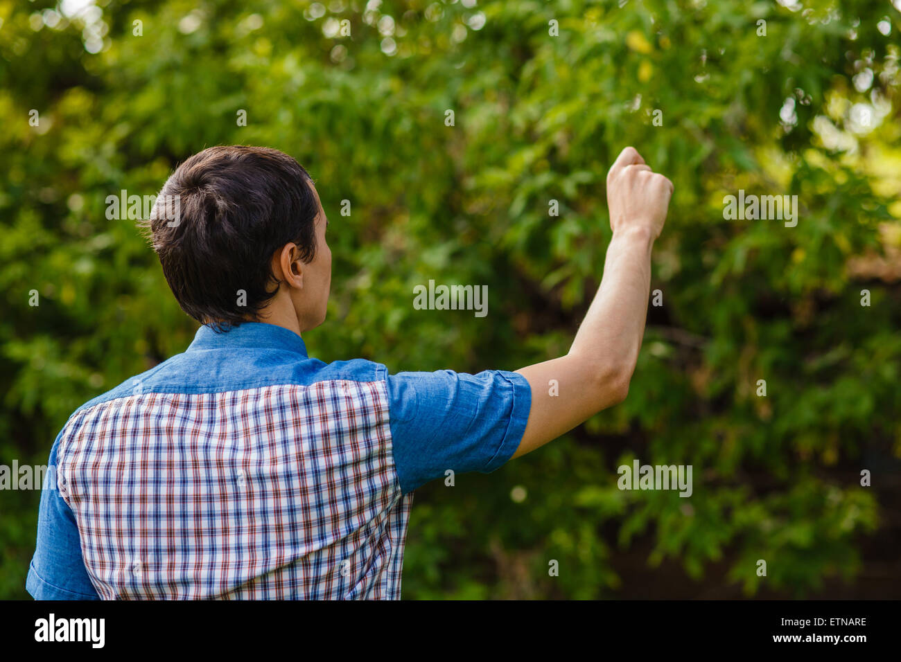 Indietro man mano che scrive in aria su uno sfondo verde street Foto Stock