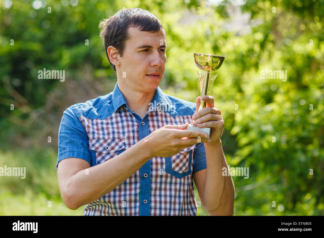 L'uomo tenendo un sports cup su strada la vittoria contro il verde Foto Stock