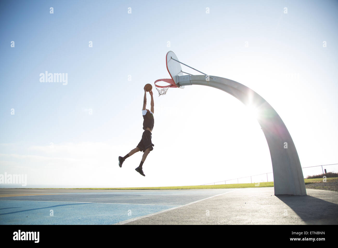 Giovane uomo giocando a basket in un parco di Los Angeles, California, Stati Uniti d'America Foto Stock