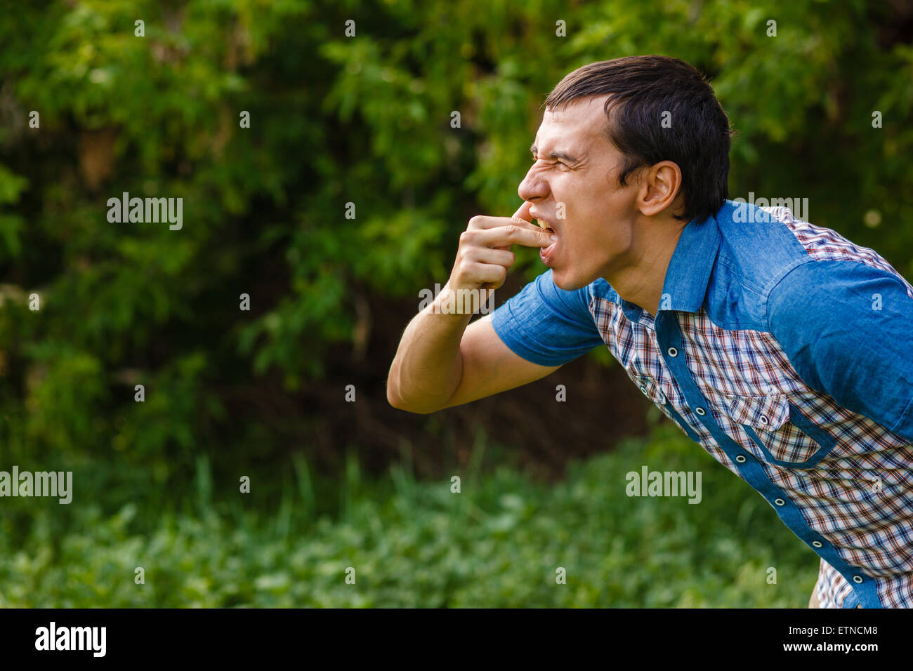 Uomo di strada nausea vomito su uno sfondo verde foglie Foto Stock