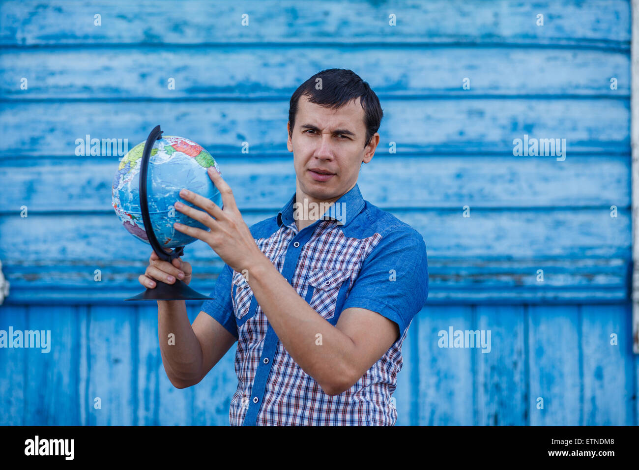 L'uomo della strada tenendo un globo mostra di lui su uno sfondo blu Foto Stock