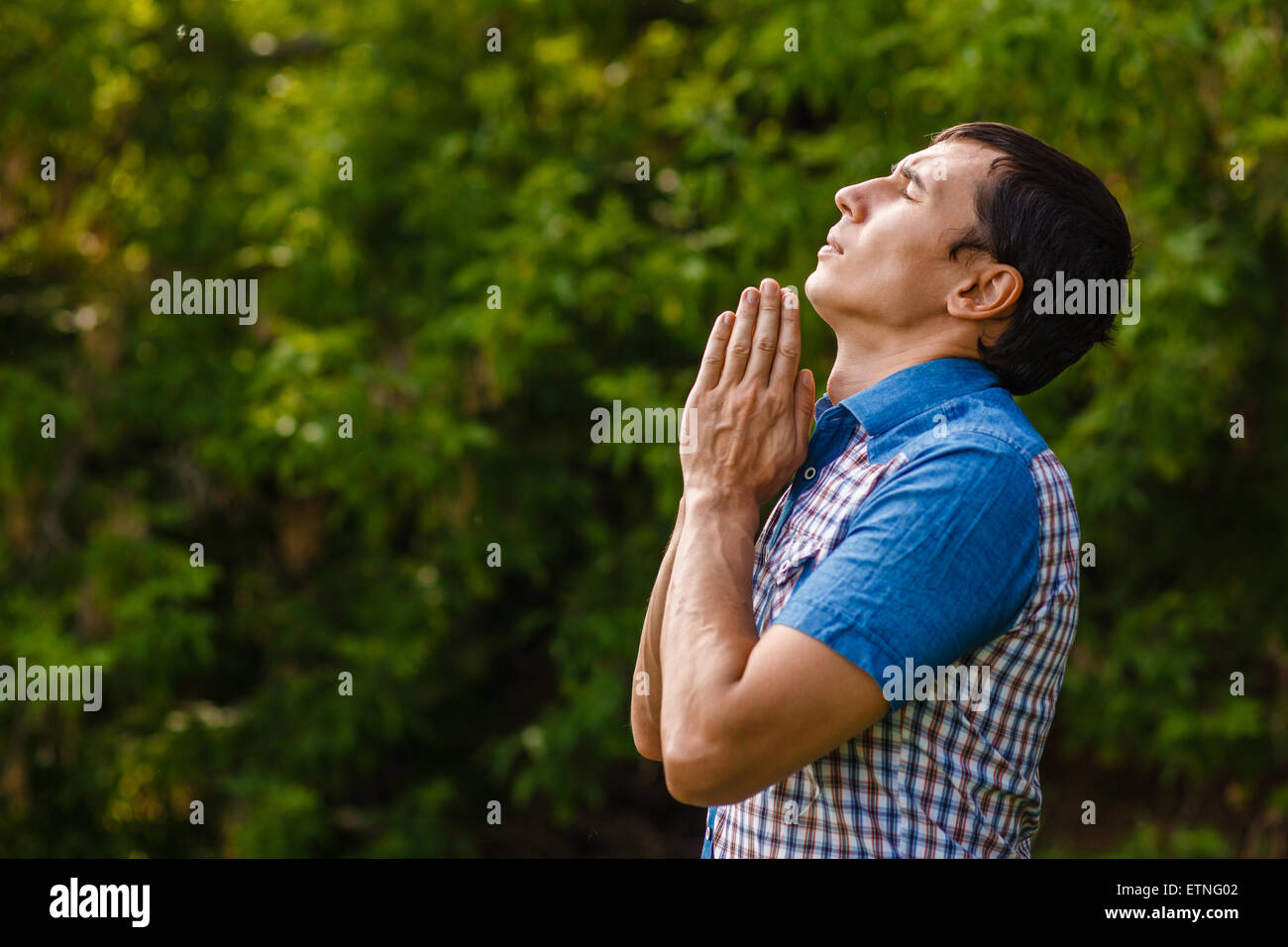 L'uomo della strada a pregare Dio su uno sfondo verde leav Foto Stock