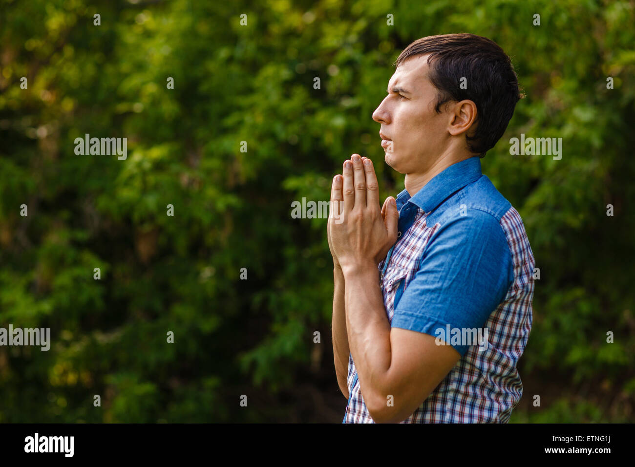L'uomo della strada a pregare Dio su uno sfondo verde lasciare Foto Stock