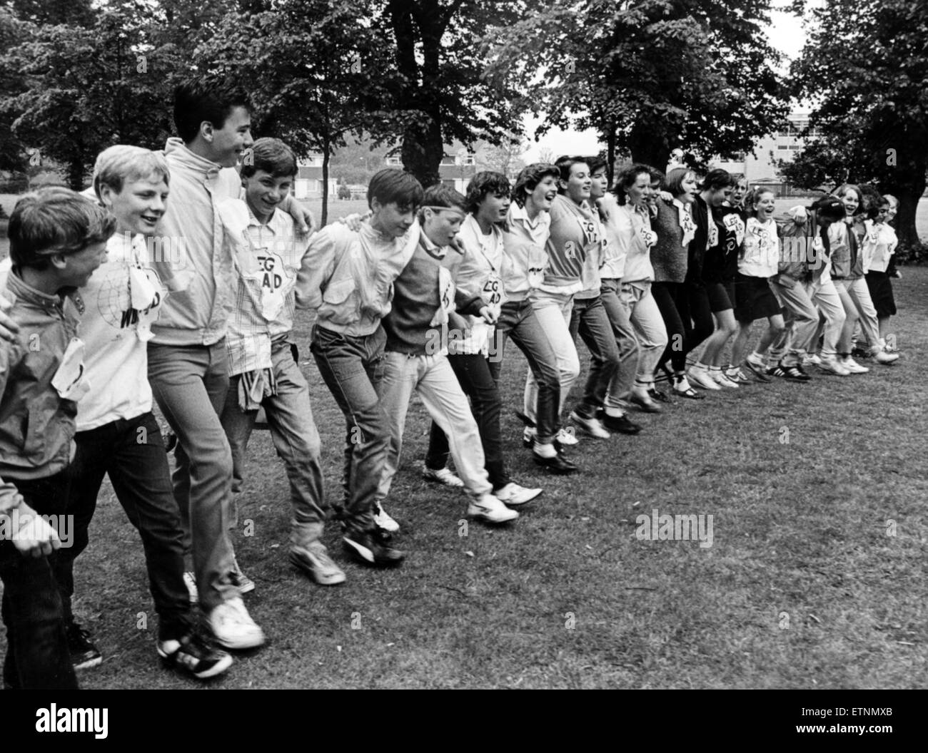 Soddisfare la scuola Hustler polypod! La carità degli scuotipaglia stessi legati in nodi e mettere le loro migliori piedi avanti oggi per sollevare il pagamento in contanti per Live Aid. La catena caotica è stato a causa del vento stesso attorno al Middlesbrough campo scuola per cinque ore! E il madcap giovani sono sperando che le estenuanti trek vincerà loro una voce nel libro del Guinness dei primati. Il 7 luglio 1986. Foto Stock