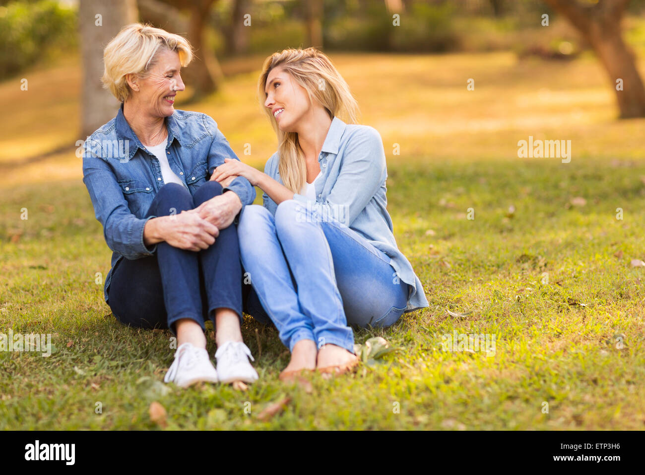 Allegro medio di età compresa tra madre e figlia giovane chiacchierando al parco Foto Stock